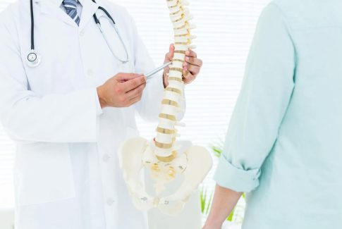Medico señalando vertebras de la columna a un paciente